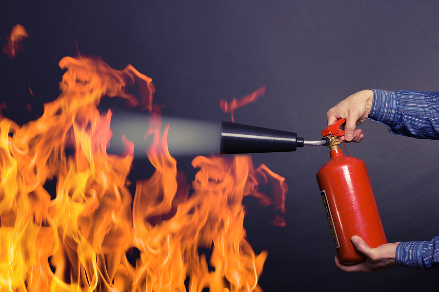 Male hand with a fire extinguisher extinguish the fire.